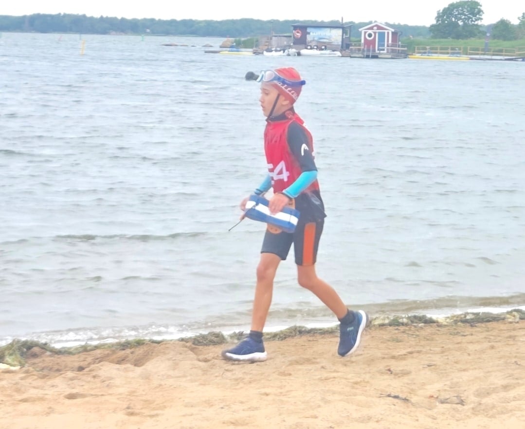 Deltagare med startnummer 54 springer längs strandkanten med dolme i handen