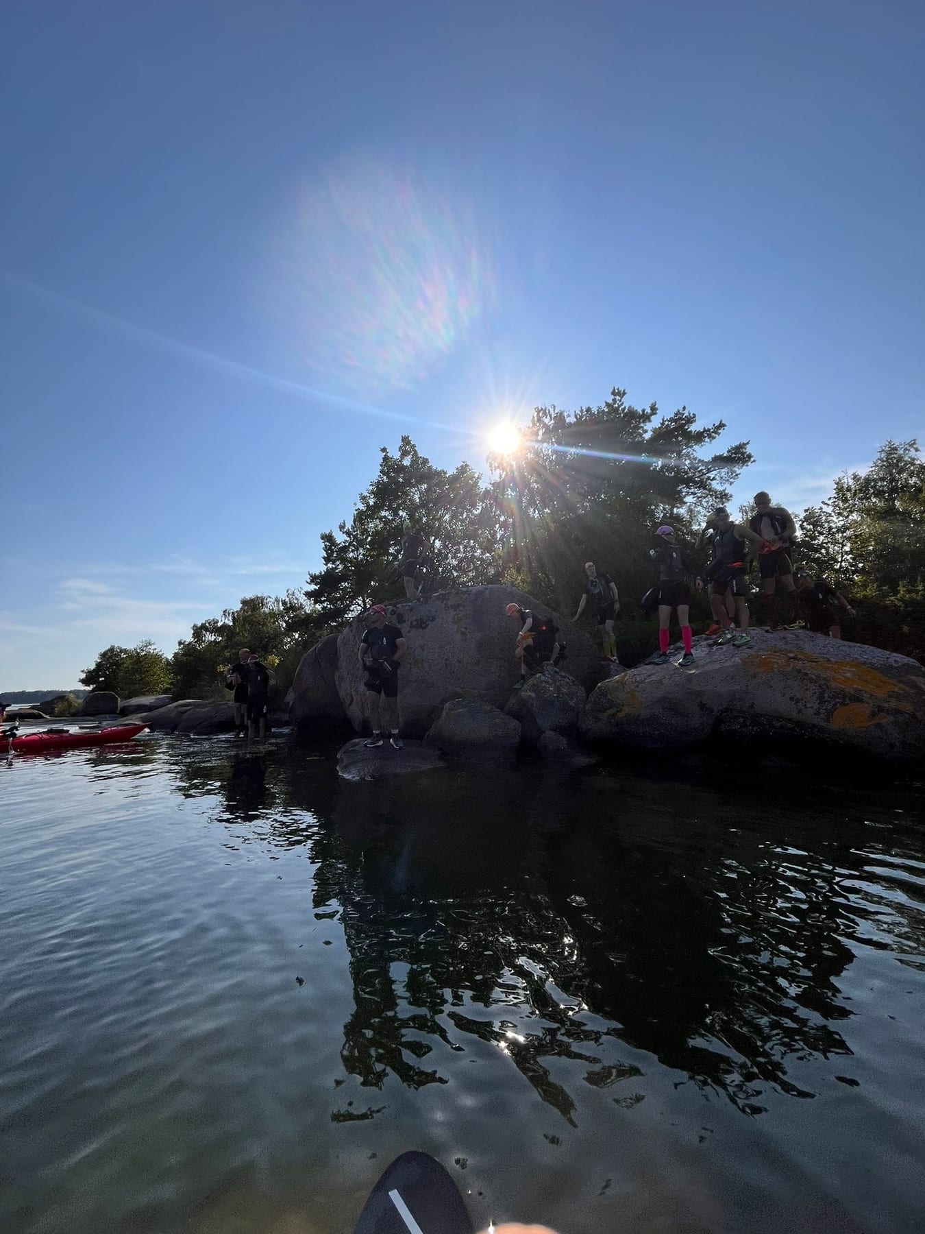 Sunset over the archipelago, athletes silhouetted on the rocks