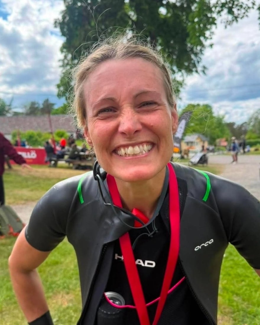 Josefine Jangvert ler stort efter ett lopp, i våtdräkt med simglasögon runt halsen